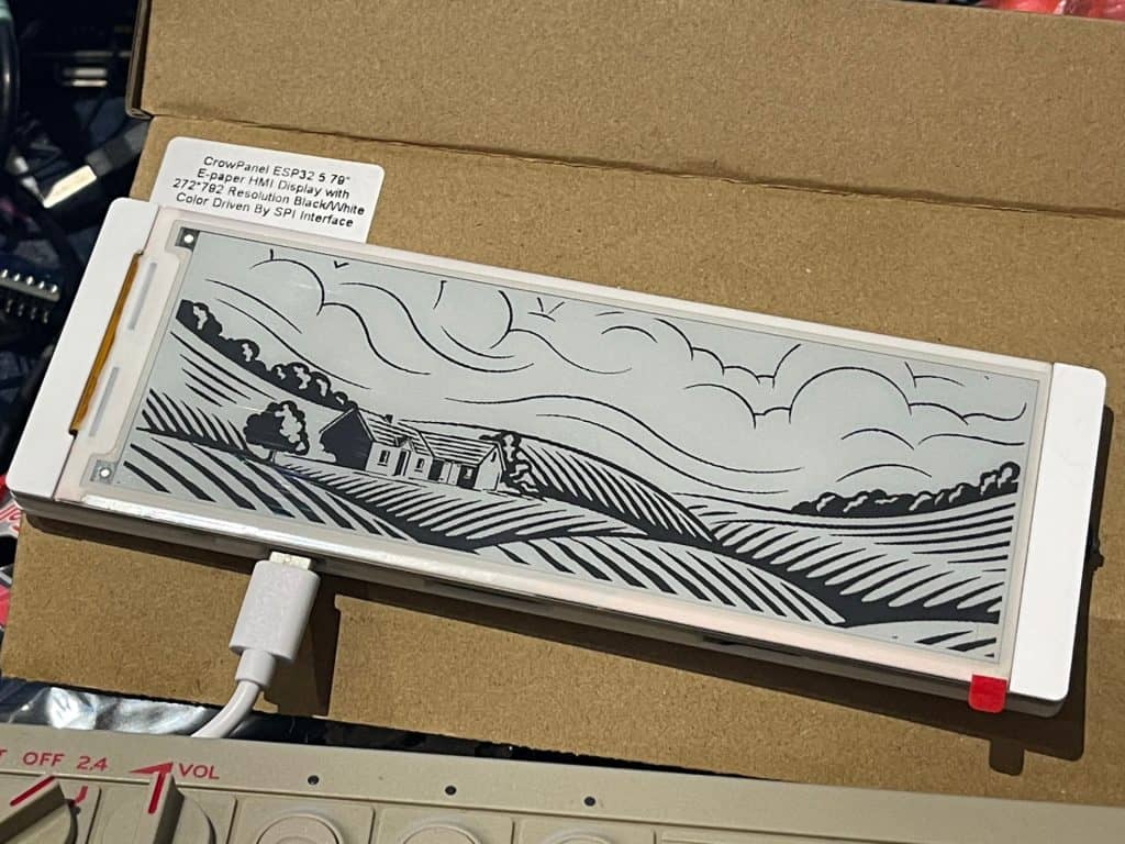 Acrylic e-paper display with countryside landscape design, used for DIY electronics projects.
