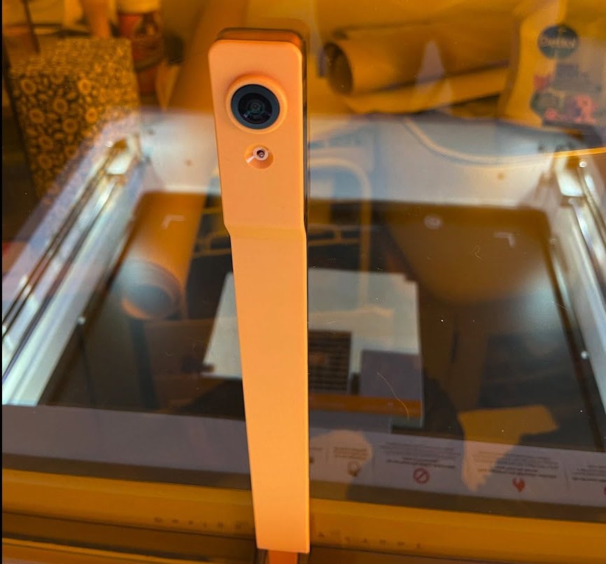 Close-up of xTool M2 laser engraver with orange housing and camera lens.